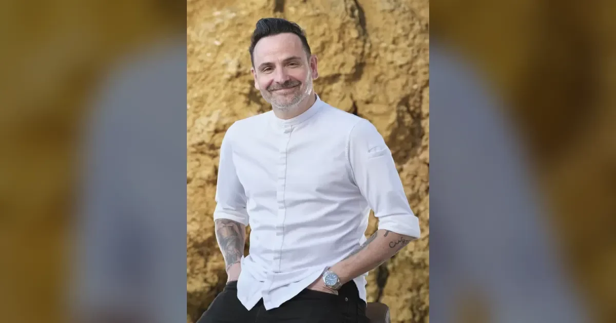 Sternekoch in weißer Kochkleidung vor Felsenkulisse an der Algarve